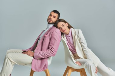 Resmi olarak şık bir çift koltuklarda oturup gri, modern moda kameralara bakıyorlar.