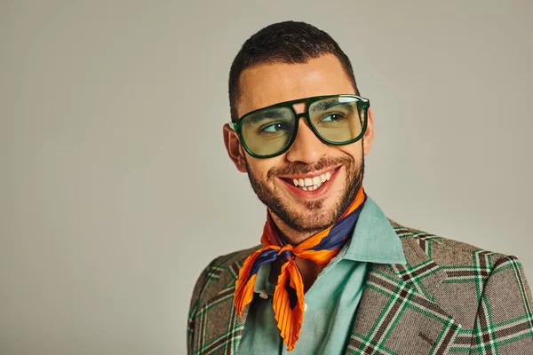 stock image happy man in plaid jacket and bright neckerchief with sunglasses looking away on grey, vintage style