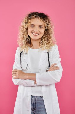 Göğüs kanseri farkındalığı, kıvırcık kadın doktor kameraya bakıyor, pembe fon, gülümseme, kadın