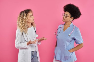 oncologists chatting, interracial doctors in white coats on pink backdrop, breast cancer awareness clipart