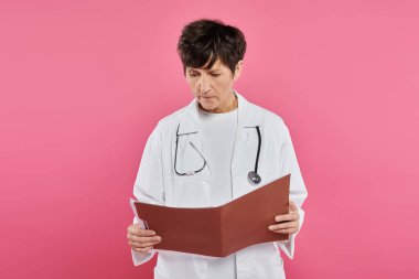 Orta yaşlı onkolog, dosyalara bakan kadın doktor, meme kanseri farkındalığı konsepti, teşhis