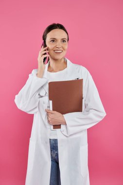 Göğüs kanseri farkındalığı, kadın doktor, mutlu onkolog akıllı telefondan konuşuyor, online danışmanlık