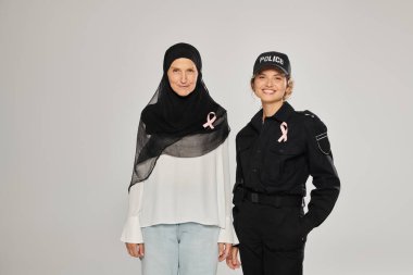 Gülümseyen kadın polis ve kadın tesettürlü pembe kurdeleli göğüs kanseri grisi