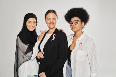 Gülümseyen ırklar arası pembe kurdeleli kadınlar. Griye sarılıyorlar.