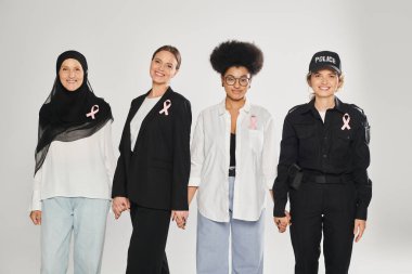 Gri ve meme kanserine izole edilmiş pembe kurdeleli pozitif çok ırklı ve farklı kadınlar.