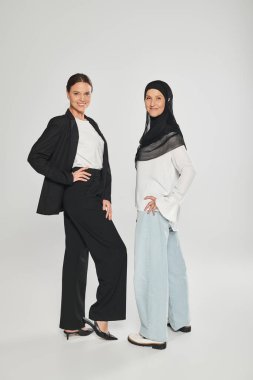 Gri arkaplanda poz veren tesettürlü iş kadını ve kadının tam uzunluğu