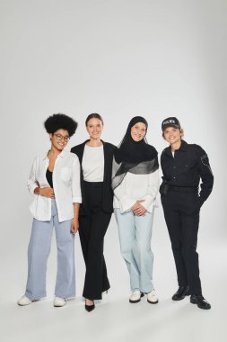 Gri arka planda bir arada duran farklı ve çok ırklı kadınlardan oluşan bir grup.