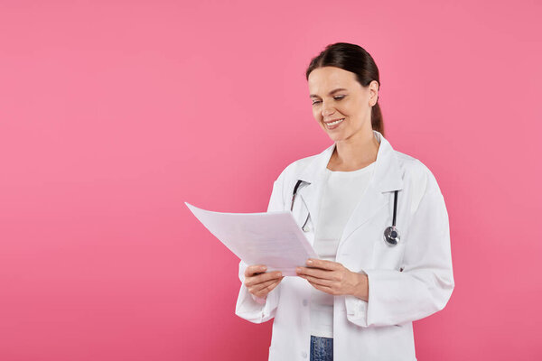 breast cancer awareness, female doctor, happy oncologist looking at mammogram, pink backdrop