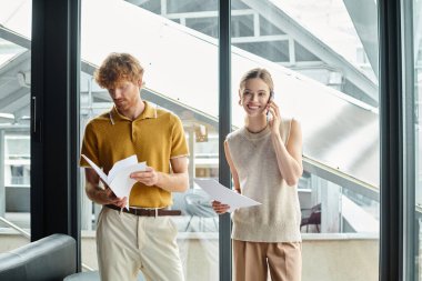 two coworkers looking at working papers and talking on phone with glass backdrop, coworking clipart