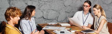 Masada oturan, birlikte çalışan, pankartta çalışan dört çalışkan iş arkadaşı.
