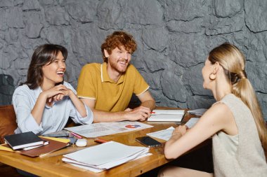 three cheerful coworkers laughing and looking at each other while working on papers, coworking clipart