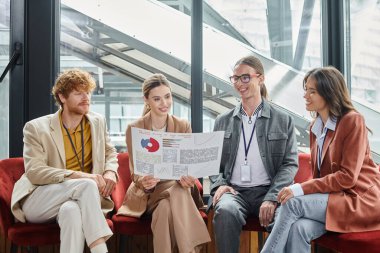 creative team looking at their paperwork with chart while sitting on chairs, coworking concept clipart