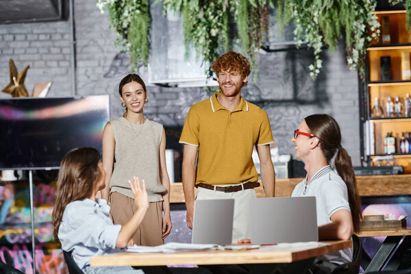 трудолюбивая команда разговаривает друг с другом во время работы над документами с помощью ноутбуков, коворкинг концепция