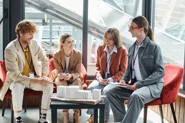 молодые члены команды, работающие вместе на масштабе модели холдинга документы и телефон, дизайн-бюро