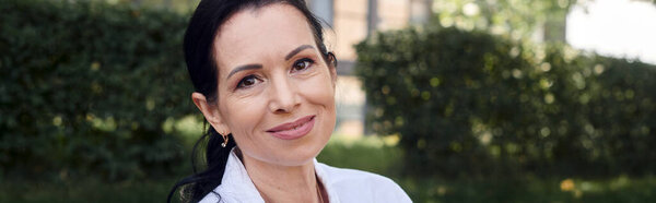 cheerful middle aged woman looking at camera during park outing, portrait, banner