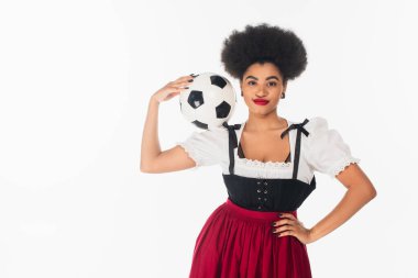 Mutlu Afro-Amerikan Bavyera garsonu Dirndl futbol topuyla poz veriyor ve elini beyaza koyuyor.