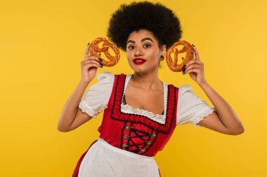 Gülümseyen Afrikalı Amerikan Ekim Festivali garsonu Dirndl 'de leziz krakerler gösteriyor.