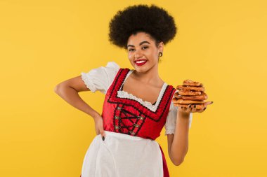 Geleneksel kostüm giymiş, elinde çubuk kraker olan ve sarıya gülümseyen Afro-Amerikan Ekim Festivali garsonu.
