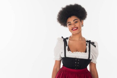 Geleneksel Dirndl kostümüyle beyaz kameraya gülümseyen mutlu Afro-Amerikan Bavyera garsonu.