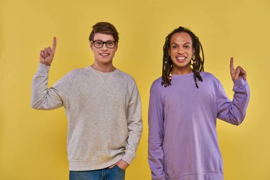 two multicultural men in casual outfits standing with fingers pointing up, cultural diverse clipart