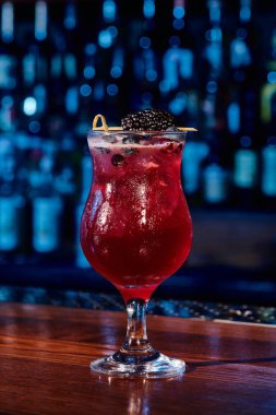 Serinletici bir bardak böğürtlen kokteyli ve bar zeminli dut süslemesi, konsept