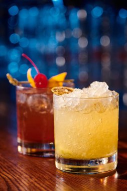 Egzotik caipirinha ve negroni buzla süslenmiş ve meyveyle süslenmiş arka planda bar, kavram