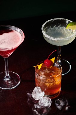 freshening margarita, cosmopolitan and negroni with ice cubes on black backdrop, concept clipart