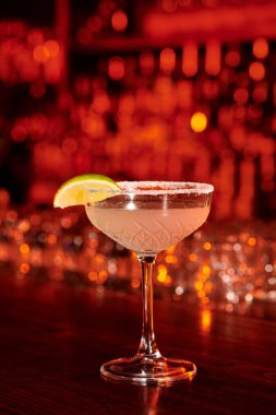 Bar tezgahında limon dilimi ve buzla süslenmiş sofistike margarita kokteyli.