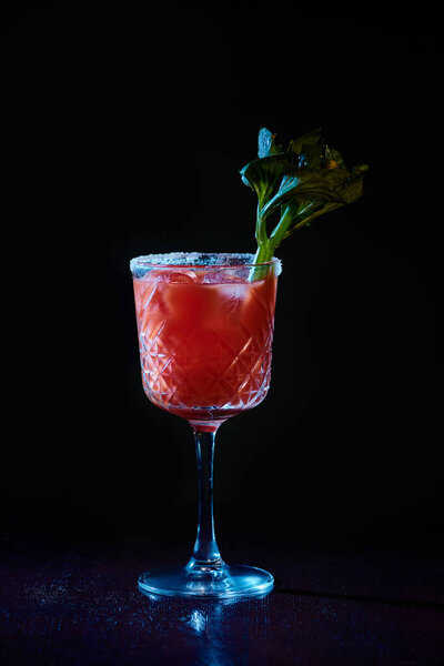 refreshing bloody mary cocktail with ice and celery stalk on black backdrop, concept