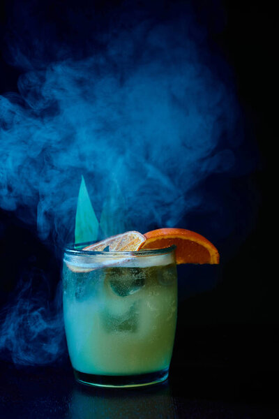 sophisticated old fashioned cocktail with garnishing on black smokey background, concept