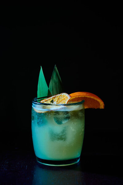 quenching old fashioned with orange slice garnishing on black background, concept