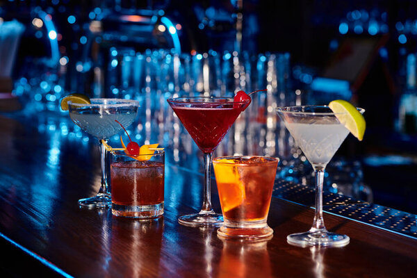 five exotic thirst quenching cocktails on bar counter with bar on backdrop, concept