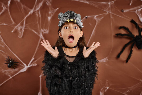 close up preteen girl looking horrified with raised hands on brown background, Halloween concept