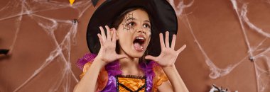 emotional girl in witch hat and Halloween costume screaming on brown background, banner clipart
