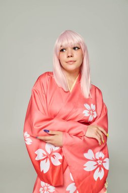 Renkli manikürlü sarışın kadın pembe kimonolu poz veriyor, gri renkli, anime tarzı çiçek desenli.
