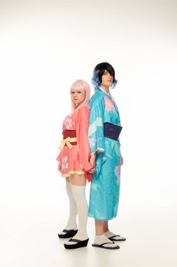 young cosplayers in colorful kimonos and wigs standing back to back and holding hands on white clipart
