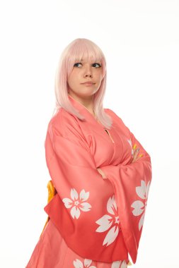 Pembe kimonolu düşünceli sarışın kadın kollarını kavuşturup beyaz kostüm modasına bakıyor.