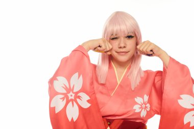 Anime kadın pembe kimonolu ve sarı peruklu, yüzünün yanında yumruklar tutan ve beyaz kameraya göz kırpan.