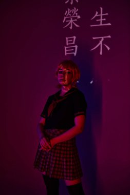 anime kadın peruk ve okul üniforması içinde neon ışıklı mor arka plan üzerinde hiyeroglifli projeksiyon.