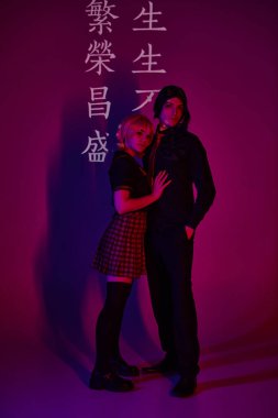 Mor zemin üzerinde neon ışıklı birkaç öğrenci hiyeroglifler ve modaya uygun kostümcüler var.