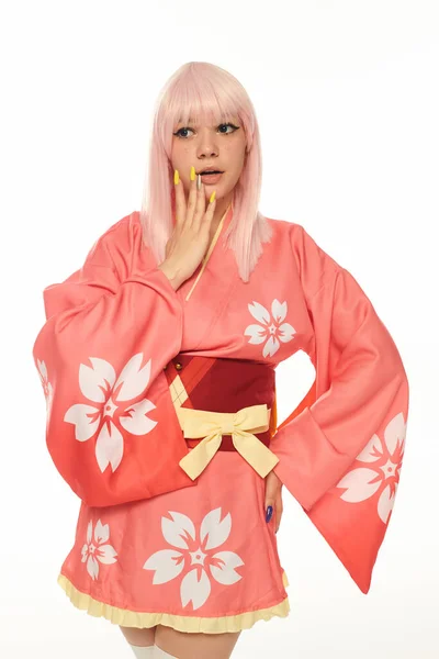 stock image shocked anime style woman in pink with hand on hip touching face on white, cosplay character