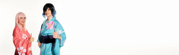 улыбающиеся косплееры в кимоно и париках, показывающие большие пальцы вверх и смотрящие в камеру на белом, баннер