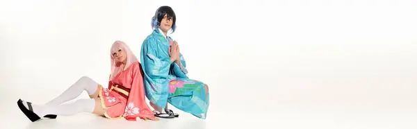 stock image man in kimono with praying hands near anime woman in blonde wig sitting on white, horizontal banner