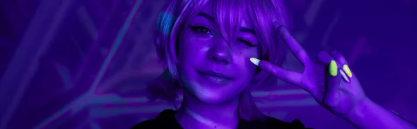 stock image anime woman with fluorescent manicure winking and showing victory sign in blue neon light, banner