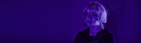 portrait of female cosplayer in blonde wig with hieroglyphs projection in blue neon light, banner