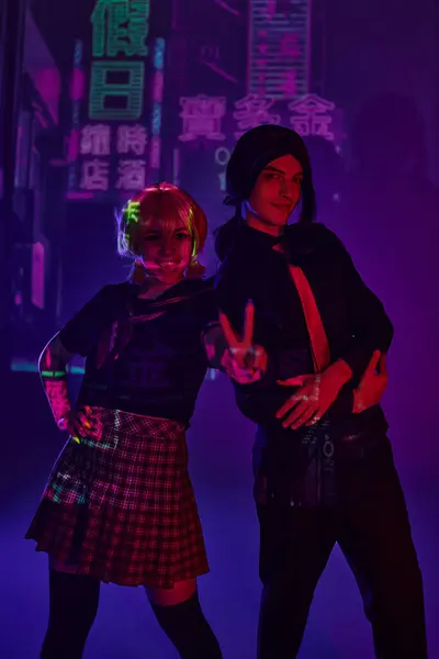 stock image anime woman in school uniform showing victory sign near man on purple neon backdrop with hieroglyphs