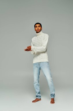 good looking african american man in white sweater with accessories posing on gray backdrop, fashion clipart