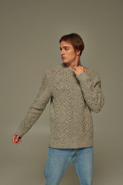 Süveterinin yakasına dokunan ve başka tarafa bakan şık bir erkek model. Moda konsepti.