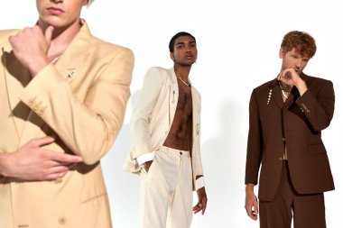 cropped view of three young diverse men posing in classy vivid suits on white backdrop, fashion clipart