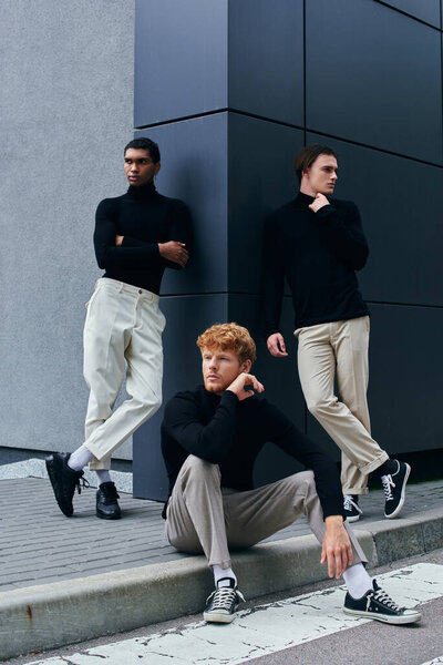 good looking multicultural men in elegant outfits posing next to wall outside, fashion concept